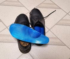 a pair of black shoes with a blue shoe cover on the floor next to them