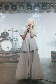 a woman standing on top of a stage holding a microphone in front of her face