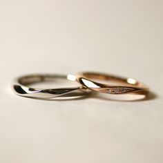 two gold wedding rings sitting on top of a white countertop next to each other