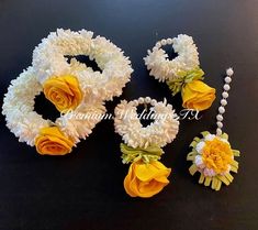 three pieces of white and yellow flowers on a black surface with pearls, beads and necklaces