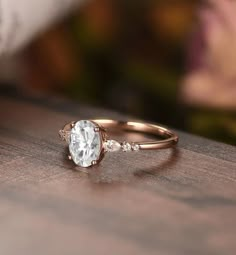 a close up of a ring on a wooden table with flowers in the background and a blurry background