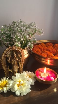 there are flowers and candles on the table next to each other with an idol in the middle