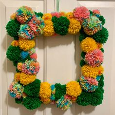 a wreath made out of pom - poms hangs on the front door's wall