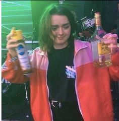 a woman holding two bottles of alcohol in one hand and an empty bottle in the other