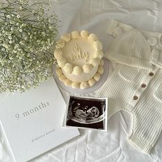 there is a cake, cardigan and baby's breath on the bed next to it