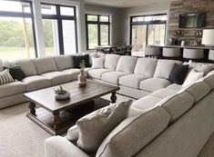 a living room filled with lots of furniture in front of large windows and floor to ceiling windows