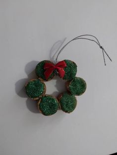 some cookies with green icing and a red bow hanging from a string on a table