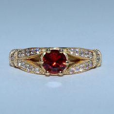 a close up of a ring with a red stone in the center and white diamonds around it