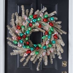 a christmas wreath is hanging on the front door with candy canes and tinsel