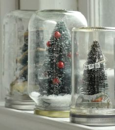 three glass jars with christmas trees in them on a window sill, one is empty