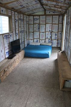 a room that has some boxes all over it and a bed in the middle with a blue blanket on top