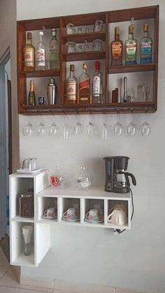 a shelf with wine glasses, cups and bottles on it next to a wall mounted spice rack