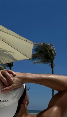 a man is holding his hat over his head on the beach with palm trees in the background