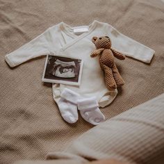 a teddy bear laying on top of a bed next to a baby's diaper