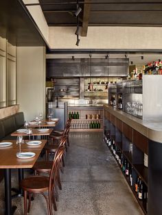 an empty restaurant with tables and chairs in front of the bar, filled with wine bottles