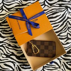 a louis vuitton wallet and keychain in a box on a zebra print surface