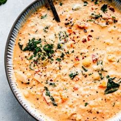 a bowl of soup with cheese and spinach on the side, ready to be eaten