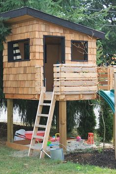 a child's play house made out of wood with a ladder to the roof