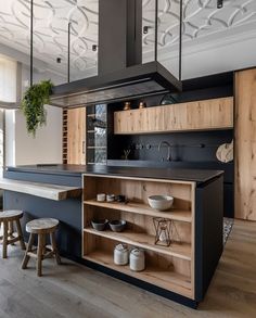 a kitchen with black counter tops and wooden cabinets, along with stools in front of the island