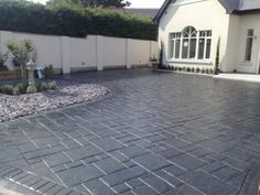 a large brick patio in front of a house with white walls and windows on the side