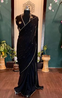 Beautiful black chinnon sari with  all over sequins and scalloped edges with an elegant dola silk brocade blouse saree fabric:chinnon length:5.5 meters blouse: 1m dola silk brocade black petticoat included Size: please choose a standard size from the drop down or you can choose custom measurements.  I'll send you a detailed measurements chart once you order. Black Georgette Pre-draped Saree With Resham Embroidery, Black Pre-draped Saree With Resham Embroidery, Celebration Dori Work Dola Silk Pre-draped Saree, Traditional Georgette Pre-draped Saree For Celebration, Pre-draped Georgette Saree For Celebration, Black Pre-draped Saree With Zari Work For Wedding, Black Georgette Bollywood Pre-draped Saree, Black Pre-draped Saree With Pallu For Festive Occasions, Unstitched Chinon Blouse Piece For Party Wear