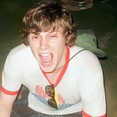 a man with his mouth open sitting on the ground