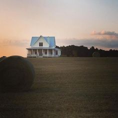 a large hay bale sitting in the middle of a field next to a house