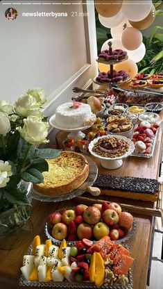 an assortment of desserts and pastries on a long table with flowers in the background