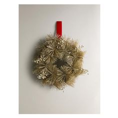 a christmas wreath hanging from the side of a white wall next to a red ribbon