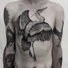 the back of a man with tattoos on his chest and arms, holding a bird