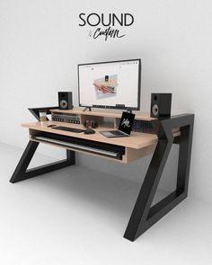 a desk with a computer and speakers on top of it in front of a white wall