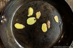 peeled bananas frying in a skillet on top of a wooden table with water