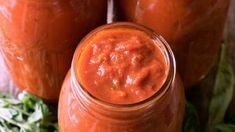 three jars filled with sauce sitting on top of a table