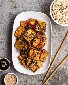 tofu and rice on a white plate with chopsticks next to the dish