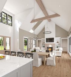 a large open concept kitchen and living room with wood flooring, white walls and vaulted ceiling