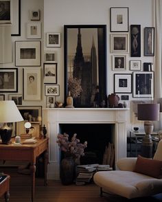 a living room filled with furniture and framed pictures on the wall above a fire place