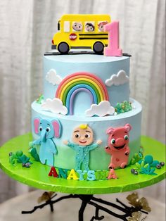 there is a cake with animals and a bus on it that is decorated like a rainbow