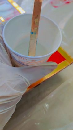 a person in white gloves is holding a bowl with a stick sticking out of it