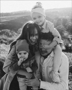 a woman and two children are posing for a photo in black and white with mountains in the background