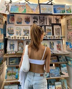 a woman standing in front of a wall with pictures and paintings on it's walls