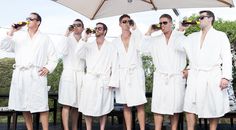 a group of men standing next to each other wearing white robes and holding drinks in their hands