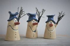 three ceramic snowmen with hats and noses on their heads, one is holding branches