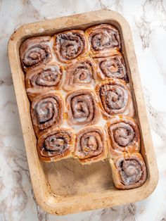 cinnamon rolls sitting in a baking pan on a marble counter top, ready to be baked