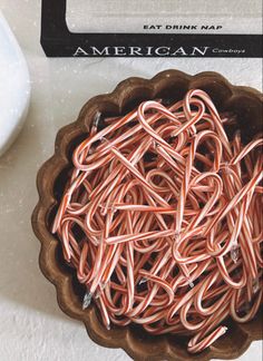 a bowl filled with lots of orange colored paper clips on top of a table next to a computer mouse