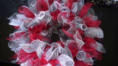 a red and white mesh wreath on a black table with glitters in the background