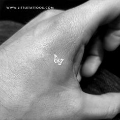 a person's hand with a small butterfly tattoo on it