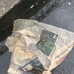 an old newspaper laying on the ground next to a puddle with water running down it