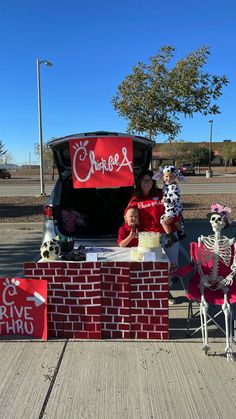 two people sitting in the back of a truck with skeletons and fake animals around it