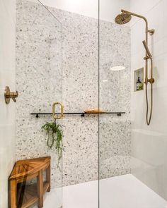 a walk in shower sitting next to a wooden bench