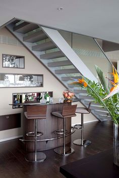 a modern bar with stools under the stairs